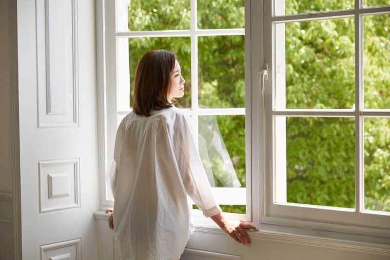 woman staring out of an open Michigan window into a yard