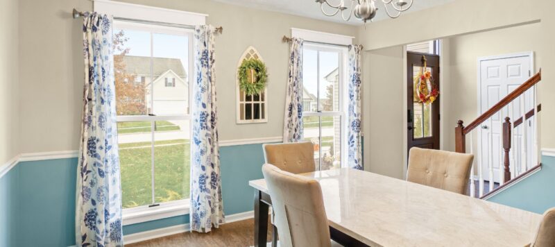 two windows in the dining room of a home with opened floral curtains