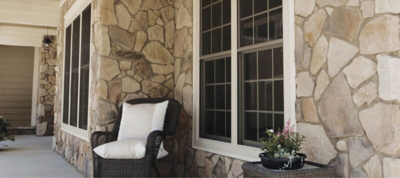 a chair on a home's front porch in between two windows