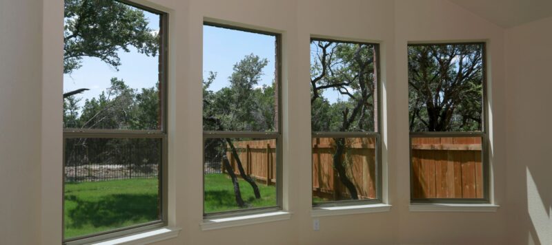 line of windows looking out into green backyard showing a fence and trees